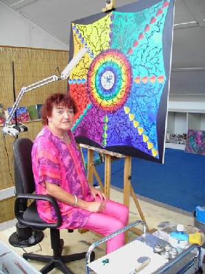 Karola assise devant une peinture dans son atelier